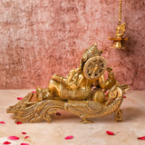 Back view of 7-inch Ganesha Idol in Brass placed on a peacock couch