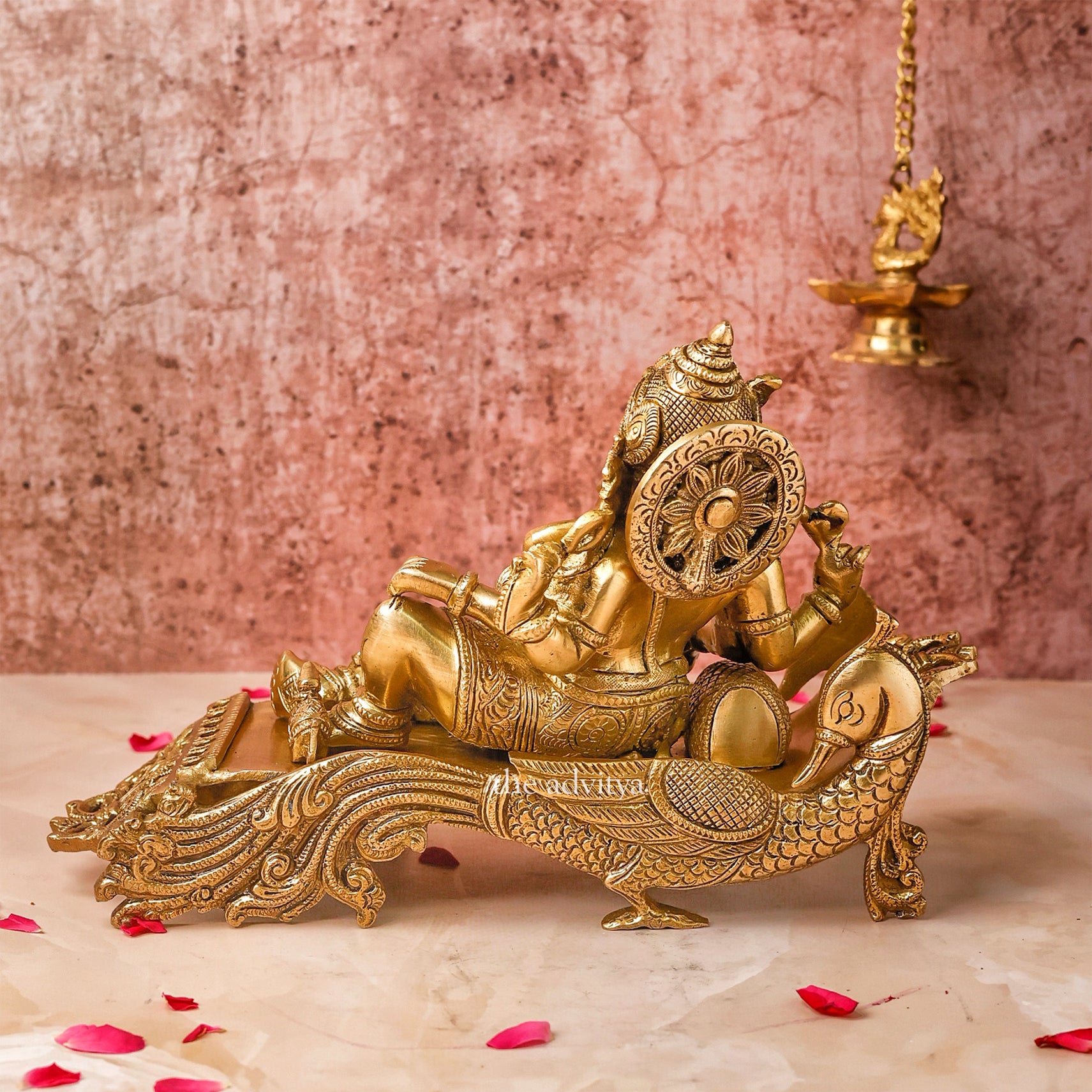 Back view of 7-inch Ganesha Idol in Brass placed on a peacock couch