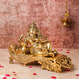 "Side view of 7-inch Ganesha Idol in Brass resting elegantly on a peacock couch"