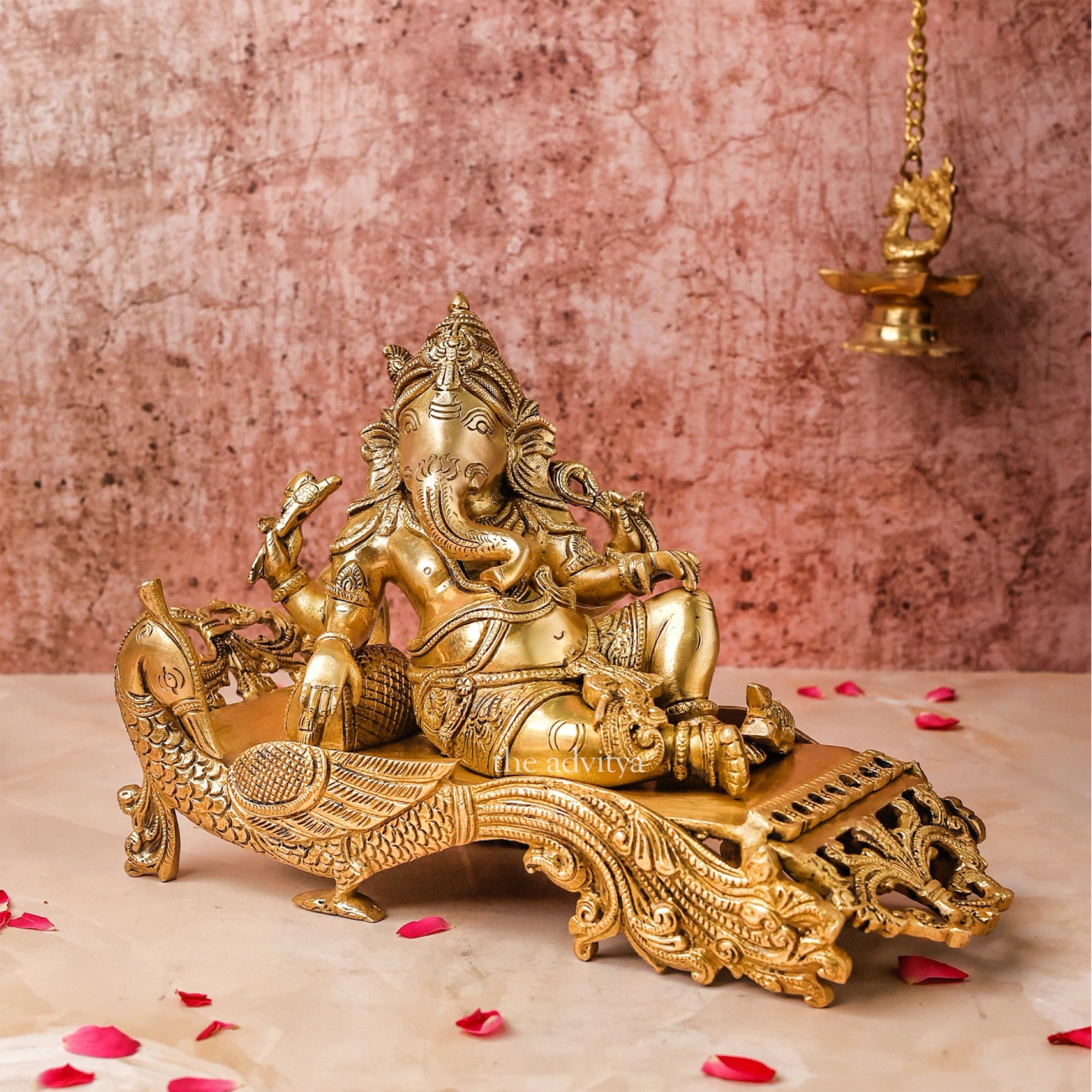"Side view of 7-inch Ganesha Idol in Brass resting elegantly on a peacock couch"