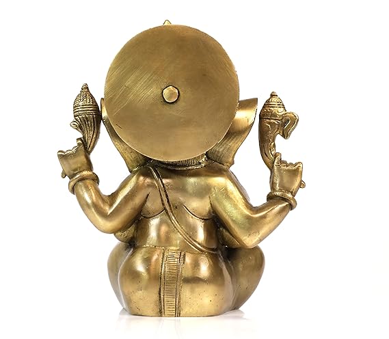 Back view of a brass Ganesha murti showing the intricately carved design on the crown and back, placed on a wooden surface with flower petals around