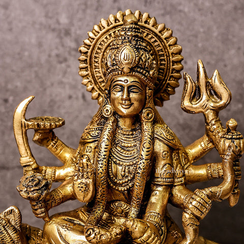 Front zoom view of brass Durga Mata Murti riding a lion on base, showcasing eight arms holding traditional weapons, with intricate detailing and regal expression.