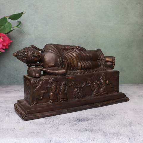 Side angle view of antique brass sleeping Buddha statue with calm facial expression