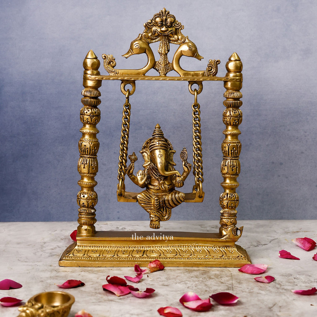 Front view of 10-inch Brass Ganpati Idol sitting on Jhula swing for Mandir décor, adding a traditional touch to your spiritual space.