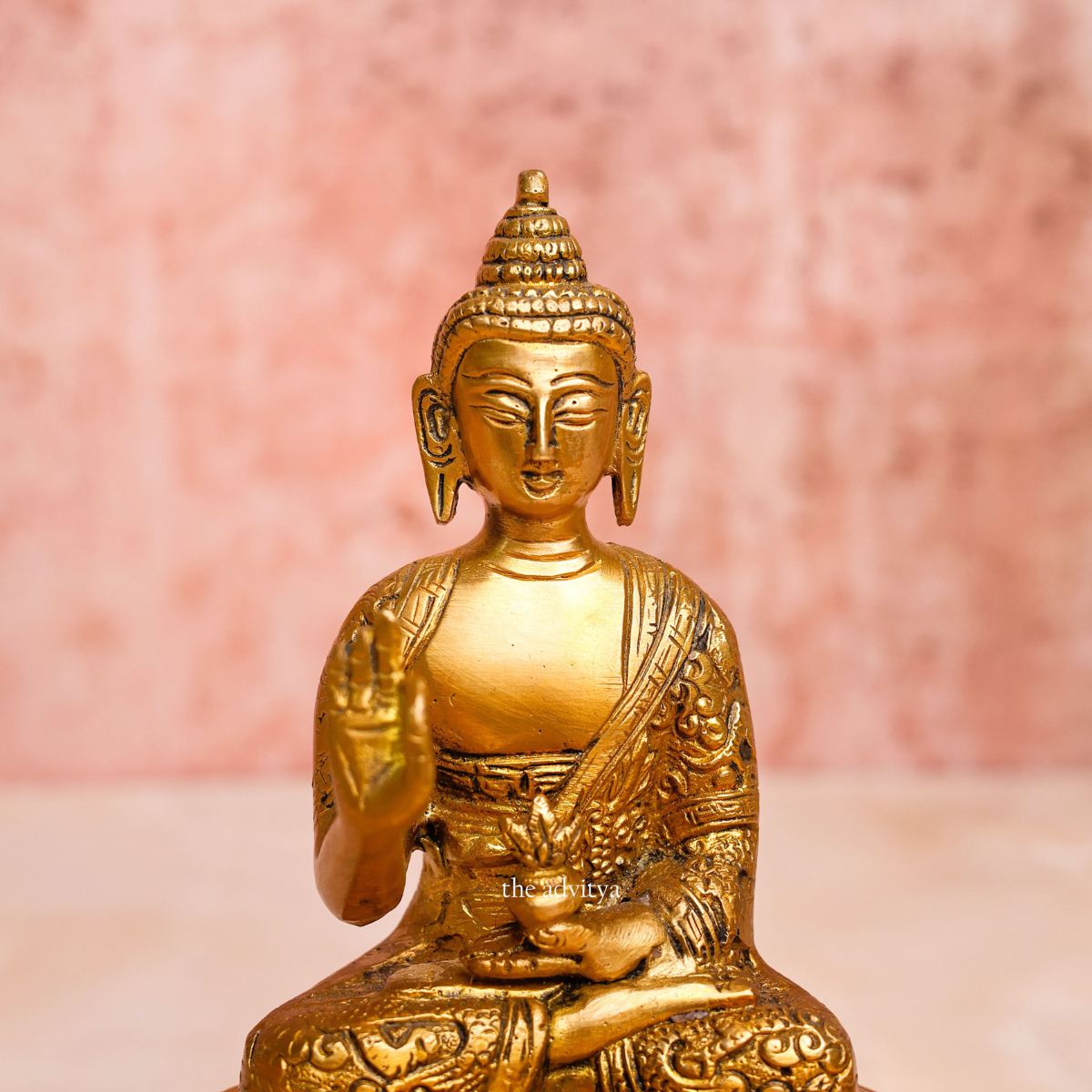 Brass handcarved blessing Buddha Murti shown from the front with serene expression and raised blessing hand close view.
