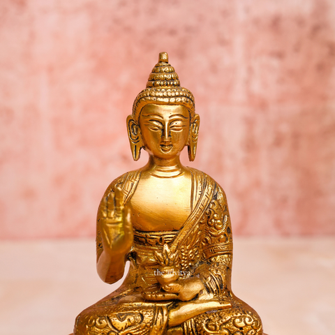 Brass handcarved blessing Buddha Murti shown from the front with serene expression and raised blessing hand close view.