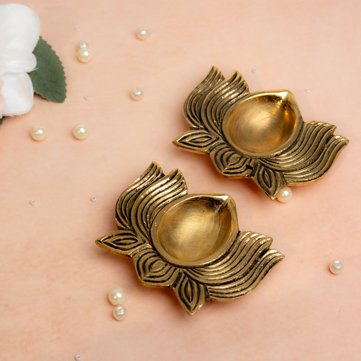 Brass lotus shaped diya set of 2 in golden finish placed.