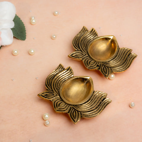 Brass lotus shaped diya set of 2 in golden finish placed.
