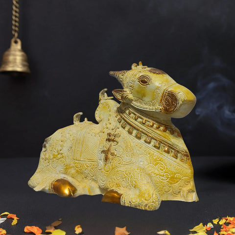 Side view of brass Nandi idol with sand finish texture and golden highlights on dark background