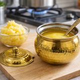 Traditional hammered brass ghee pot placed on wooden tray