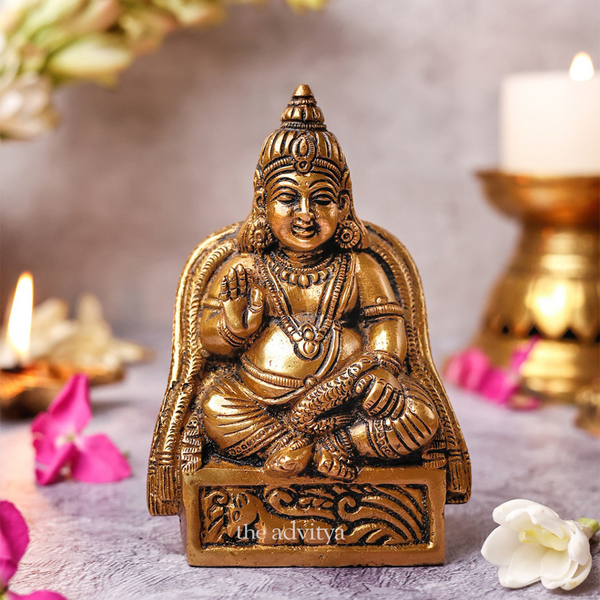 Front view of Kuber idol in sitting pose on decorative base.