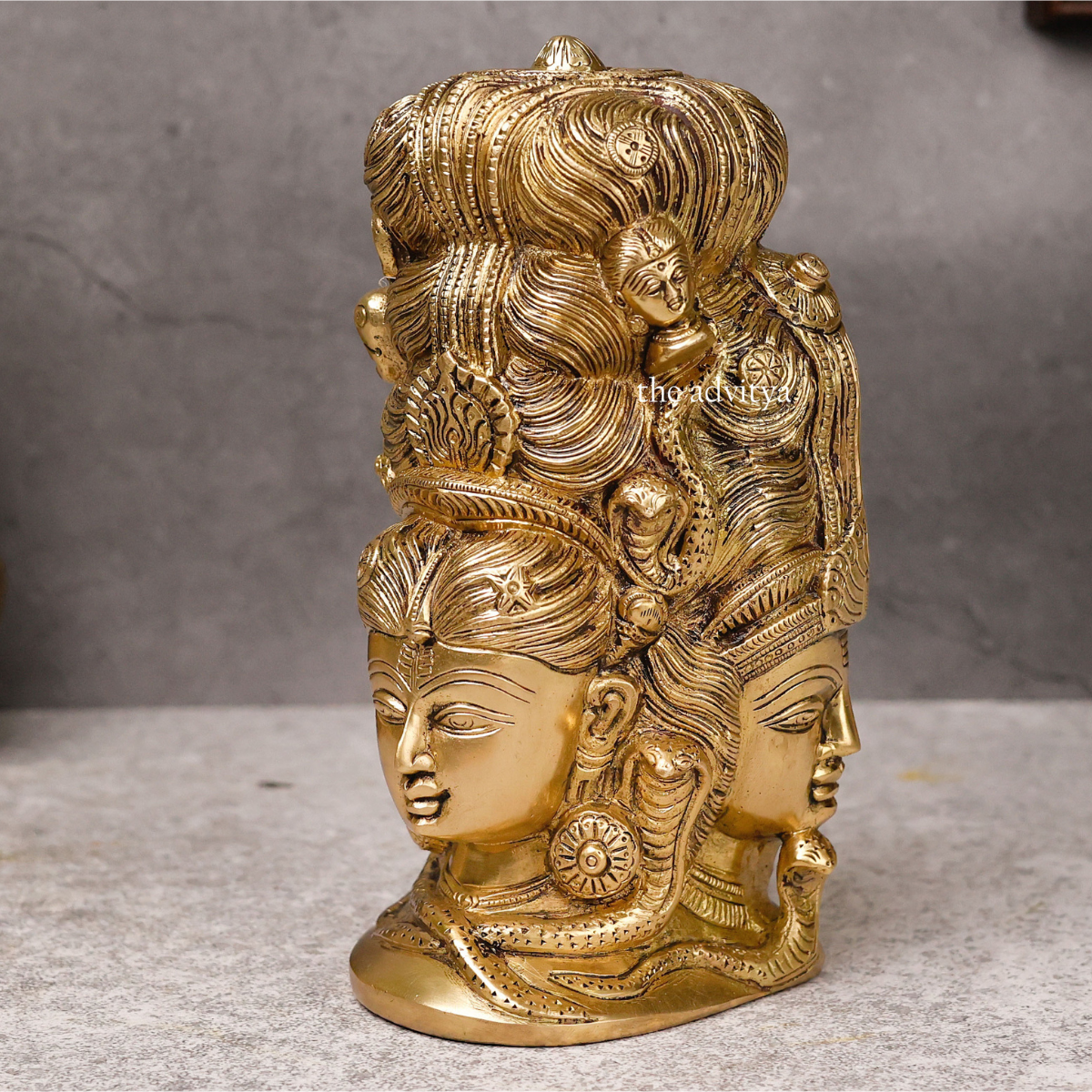 Left angle view of brass Lord Shiva statue with three faces behind Parvati.