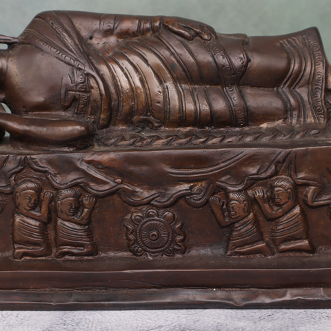 Close-up view of antique brass reclining Buddha statue with traditional design