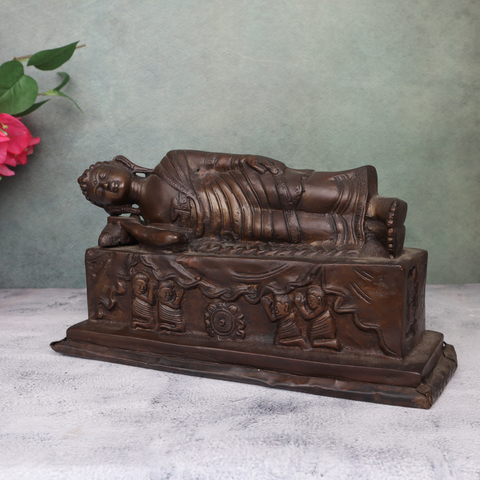 Handcrafted brass sleeping Buddha statue highlighting intricate robe and base carvings