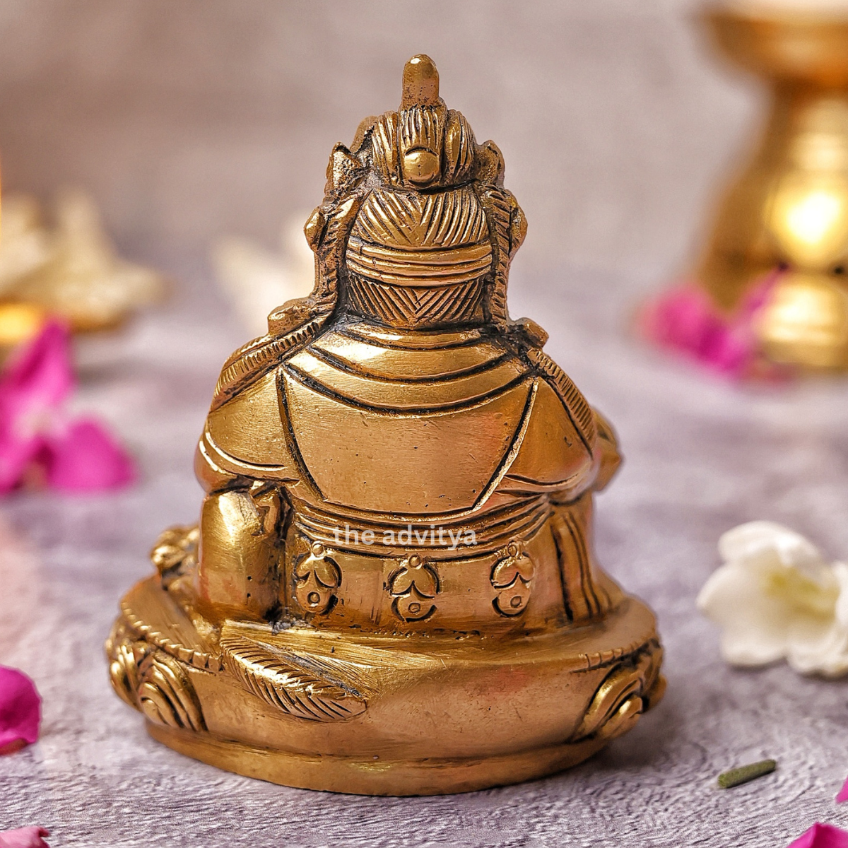 Brass back view of Kubera Statue sitting on base with detailed finishing
